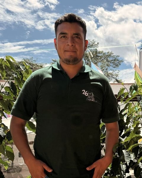 Ronaldhiño Huamán Soroe, responsable de producción sostenible y certificaciones, con polo verde de APROECO junto a cafetos.